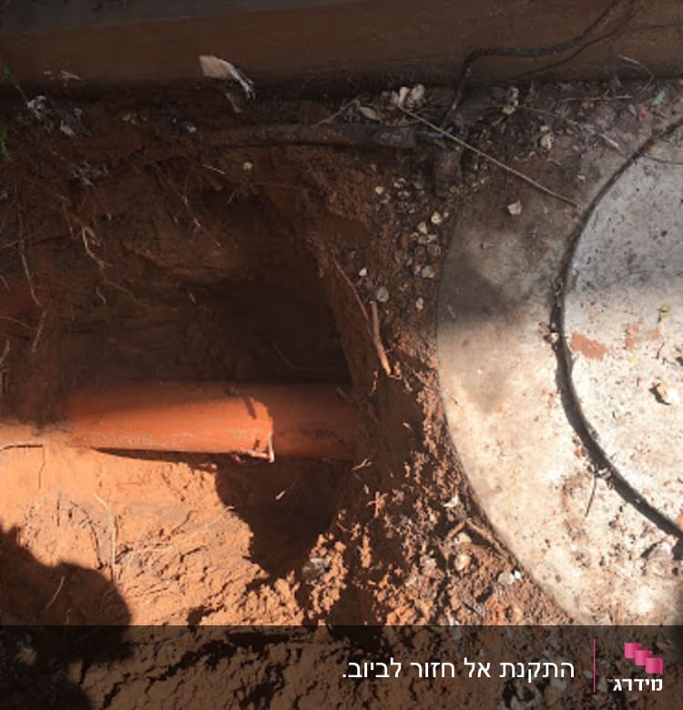 צינור כתום באדמה ליד מכסה ביוב